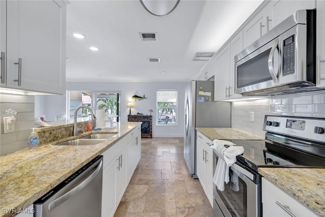 kitchen with sink, light stone countertops, tasteful backsplash, white cabinetry, and stainless steel appliances