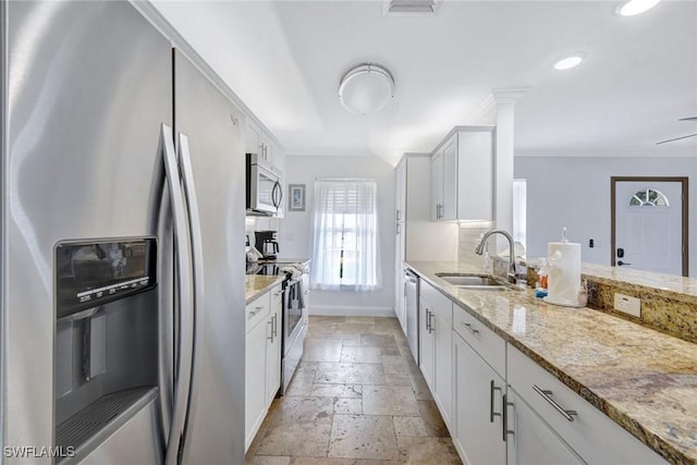 kitchen featuring light stone countertops, sink, stainless steel appliances, backsplash, and white cabinets