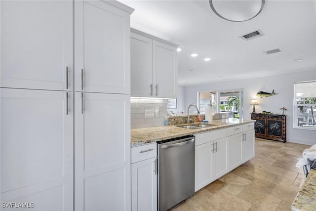 kitchen with tasteful backsplash, light stone counters, stainless steel dishwasher, sink, and white cabinets