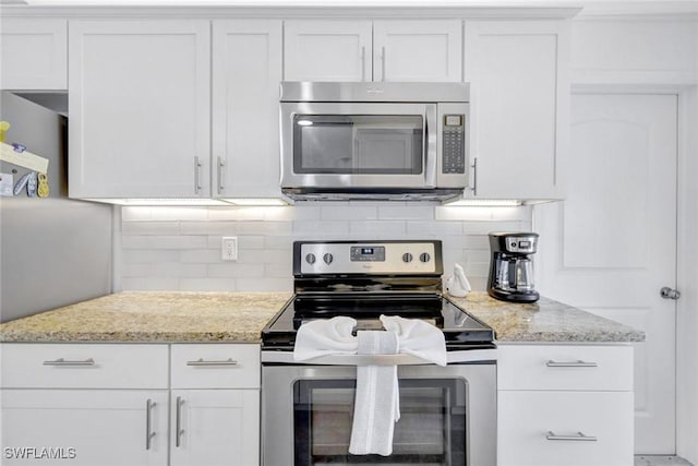 kitchen with white cabinets, light stone counters, stainless steel appliances, and tasteful backsplash