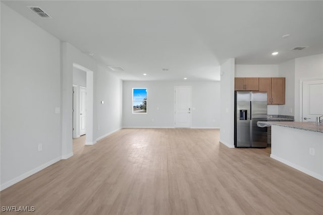 kitchen featuring stone counters, stainless steel refrigerator with ice dispenser, and light wood-type flooring