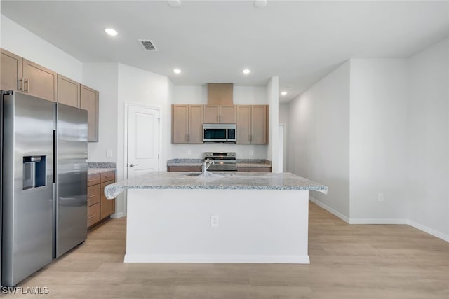 kitchen featuring a center island with sink, sink, light hardwood / wood-style flooring, light stone countertops, and stainless steel appliances