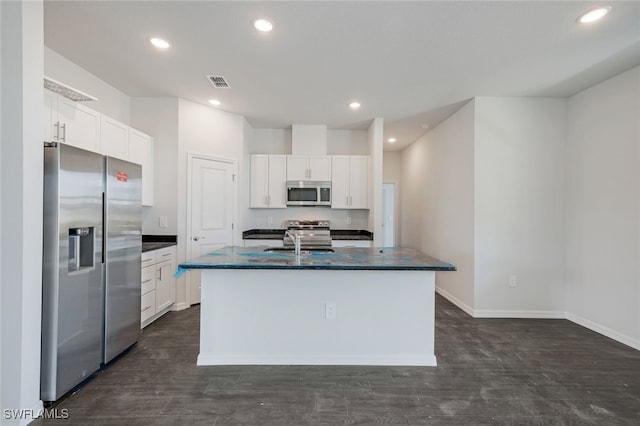 kitchen with appliances with stainless steel finishes, dark wood-type flooring, sink, a center island with sink, and white cabinetry