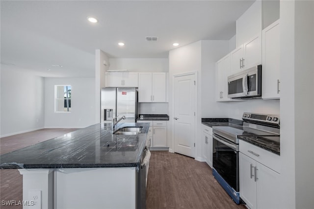 kitchen with appliances with stainless steel finishes, sink, white cabinets, dark hardwood / wood-style floors, and an island with sink