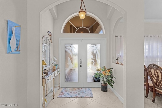 foyer entrance featuring light tile patterned flooring, crown molding, and french doors