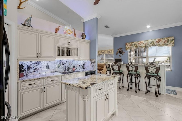 kitchen with a center island, crown molding, sink, tasteful backsplash, and stainless steel refrigerator