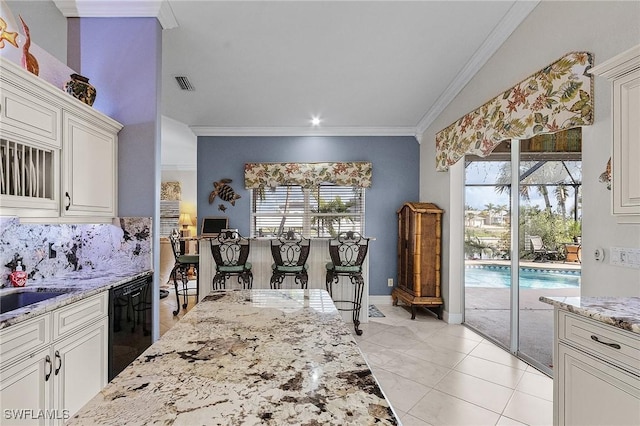 kitchen featuring plenty of natural light, white cabinets, ornamental molding, and black dishwasher