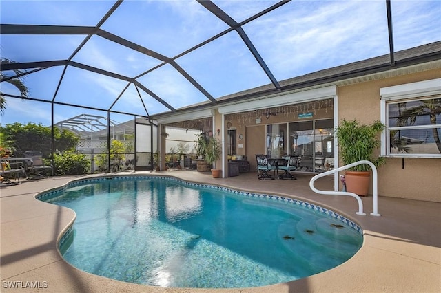 view of pool with glass enclosure and a patio area