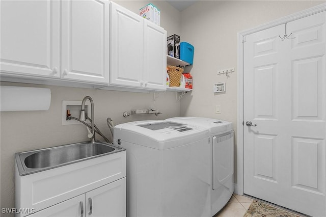 clothes washing area with washer and dryer, light tile patterned flooring, cabinets, and sink