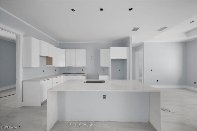 kitchen featuring white cabinetry and an island with sink