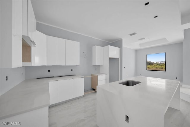 kitchen featuring white cabinets, a kitchen island, and sink