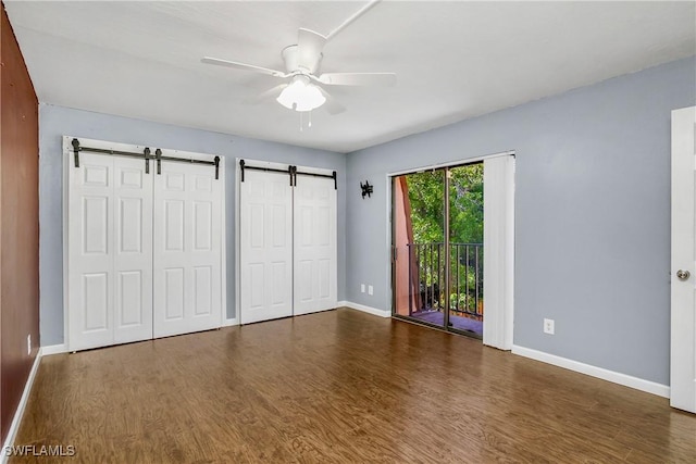 unfurnished bedroom with baseboards, ceiling fan, wood finished floors, access to exterior, and multiple closets