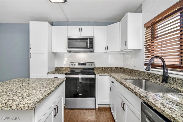 kitchen with dark wood-type flooring, sink, stone countertops, white cabinetry, and stainless steel appliances