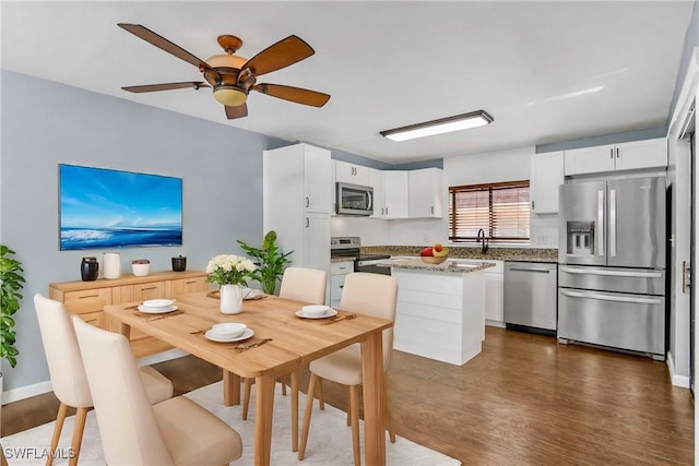 kitchen featuring appliances with stainless steel finishes, a center island, white cabinets, and dark wood-type flooring