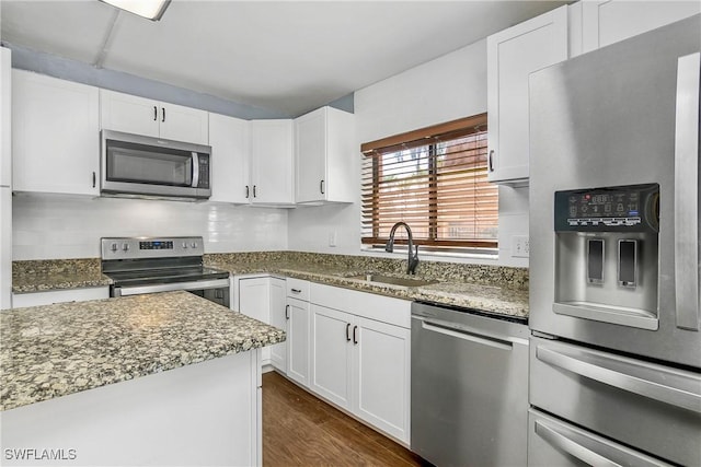 kitchen with dark stone countertops, white cabinetry, sink, and appliances with stainless steel finishes