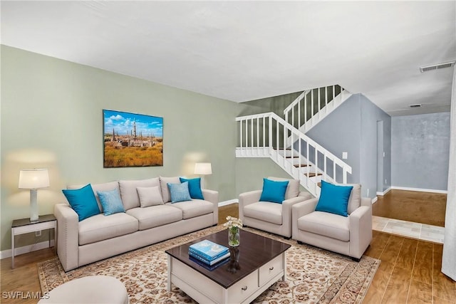 living area with visible vents, stairway, baseboards, and wood finished floors