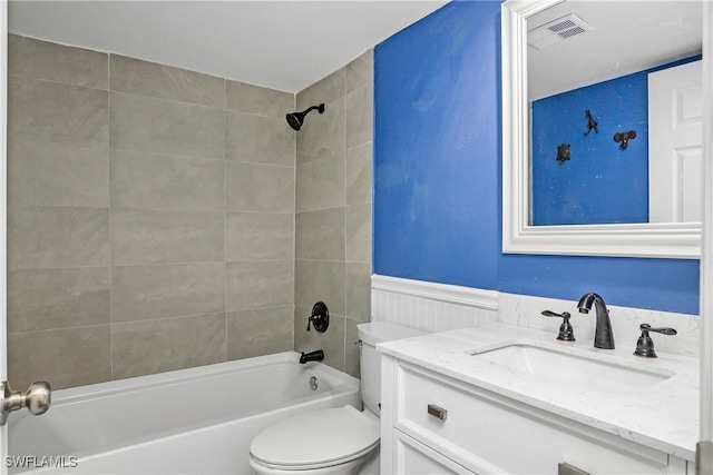 bathroom with visible vents, toilet, a wainscoted wall, vanity, and shower / bathing tub combination