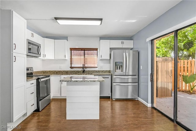 kitchen featuring stainless steel appliances, white cabinetry, stone counters, dark hardwood / wood-style floors, and a kitchen island