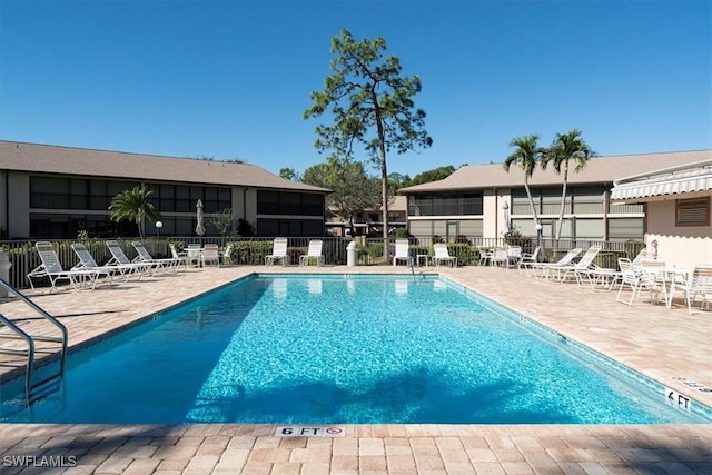 pool with a patio area and fence