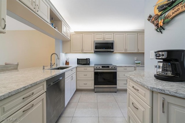 kitchen featuring light tile patterned floors, a sink, a toaster, light stone countertops, and appliances with stainless steel finishes