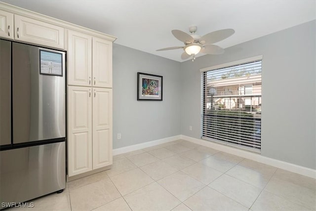 unfurnished dining area with light tile patterned floors, baseboards, and a ceiling fan