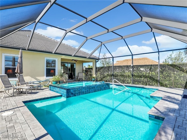 view of swimming pool with glass enclosure, ceiling fan, a patio area, and an in ground hot tub