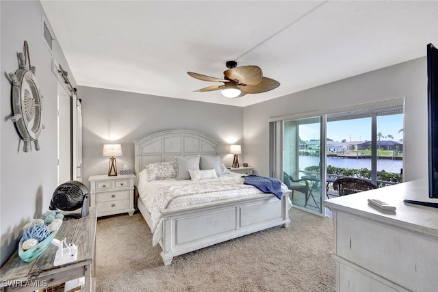 carpeted bedroom featuring access to exterior, ceiling fan, a barn door, and a water view