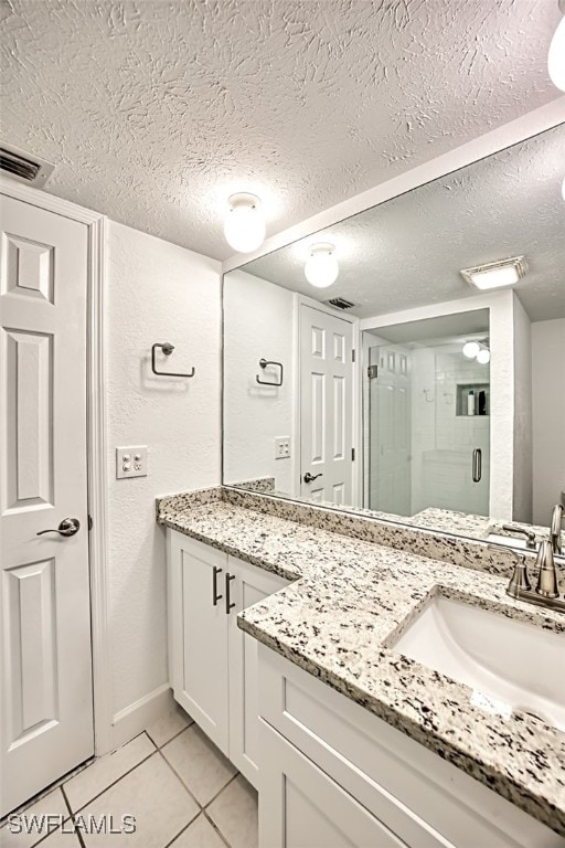 bathroom with a textured ceiling, vanity, tile patterned floors, and an enclosed shower