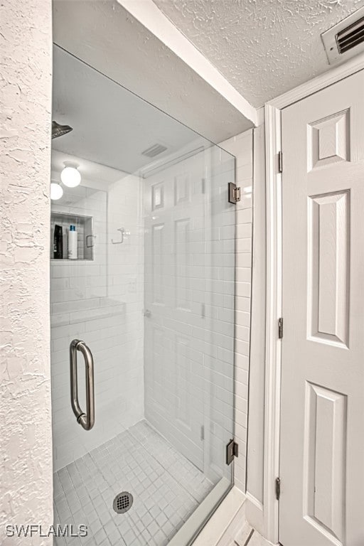 bathroom featuring a shower with door and a textured ceiling