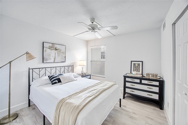 bedroom with a closet, ceiling fan, light hardwood / wood-style flooring, and a textured ceiling