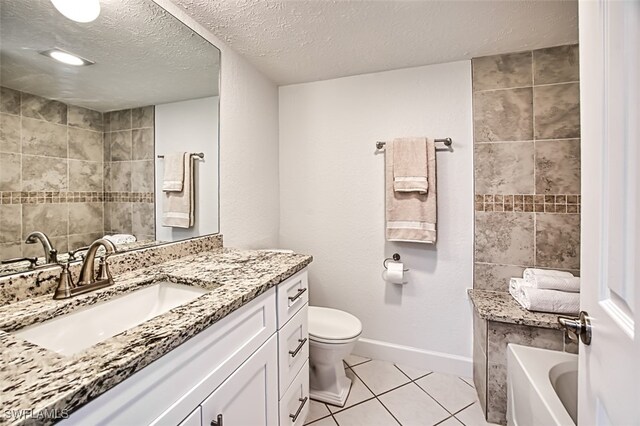 bathroom featuring vanity, a textured ceiling, a bath, tile patterned flooring, and toilet