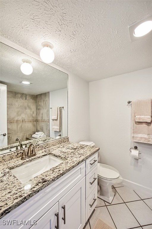 bathroom with toilet, a textured ceiling, vanity, and tile patterned floors