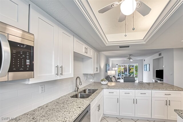 kitchen with a tray ceiling, white cabinetry, sink, and stainless steel appliances