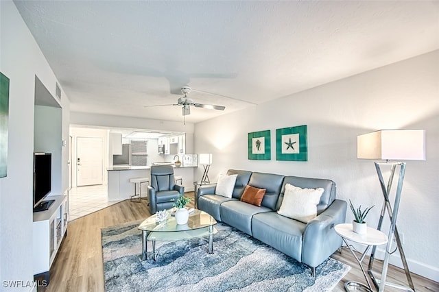 living room with ceiling fan and light hardwood / wood-style flooring