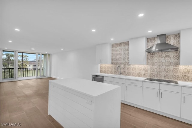 kitchen featuring expansive windows, stainless steel dishwasher, wall chimney exhaust hood, and decorative backsplash