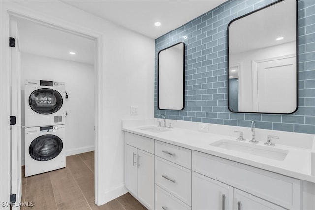 bathroom featuring double vanity, stacked washer / dryer, wood finished floors, and a sink