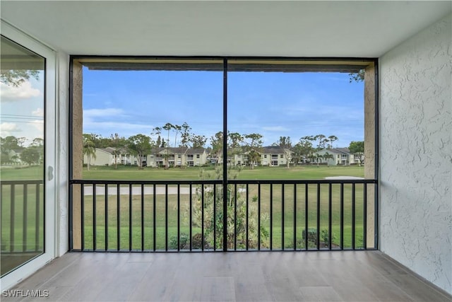 unfurnished sunroom featuring a residential view and a healthy amount of sunlight