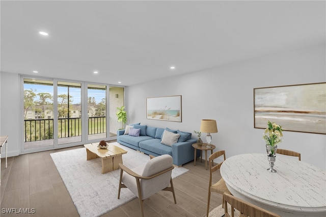 living room with floor to ceiling windows, recessed lighting, and light wood finished floors