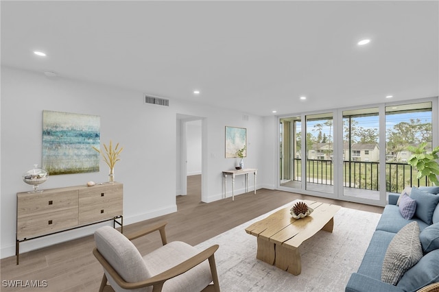 living area with recessed lighting, wood finished floors, visible vents, and baseboards