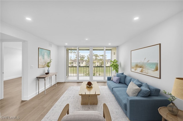 living room featuring visible vents, baseboards, recessed lighting, floor to ceiling windows, and light wood-type flooring