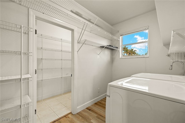 laundry area featuring washing machine and clothes dryer and light hardwood / wood-style flooring