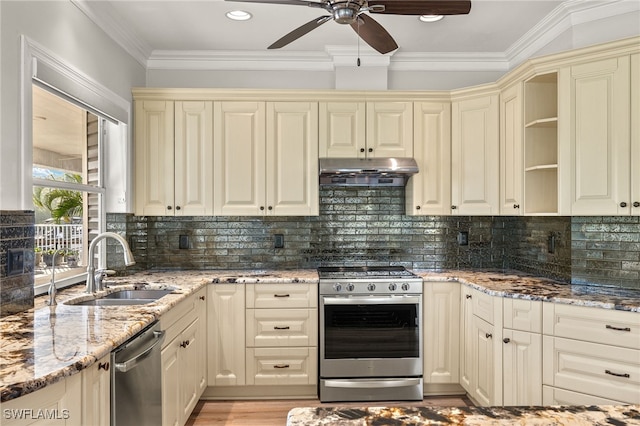 kitchen with light stone countertops, appliances with stainless steel finishes, tasteful backsplash, sink, and cream cabinets