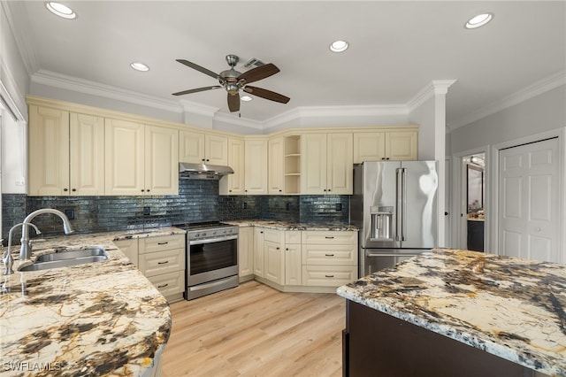 kitchen with cream cabinetry, sink, light stone countertops, and stainless steel appliances