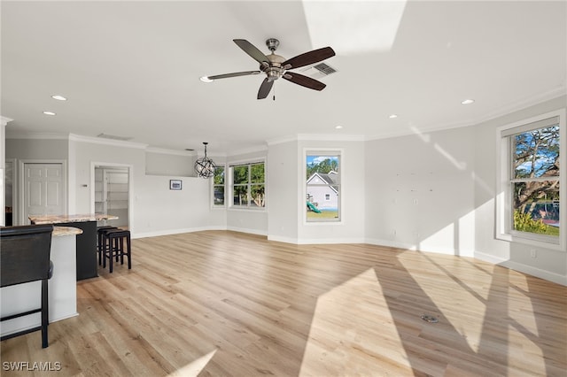 unfurnished living room with ceiling fan with notable chandelier, light wood-type flooring, and ornamental molding