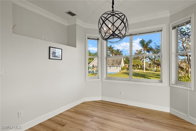 unfurnished dining area with a healthy amount of sunlight, ornamental molding, light hardwood / wood-style flooring, and a chandelier