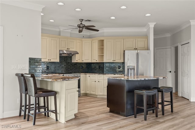 kitchen with a kitchen bar, cream cabinets, stainless steel appliances, and a kitchen island