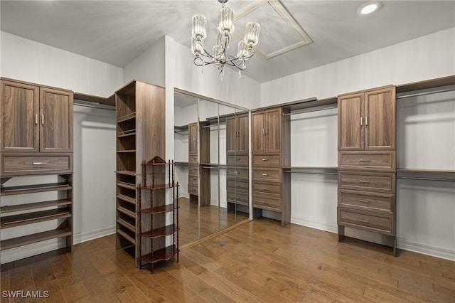 spacious closet featuring a notable chandelier and dark wood-type flooring