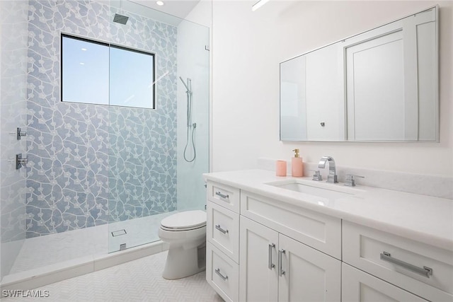 bathroom featuring toilet, a tile shower, vanity, and tile patterned floors