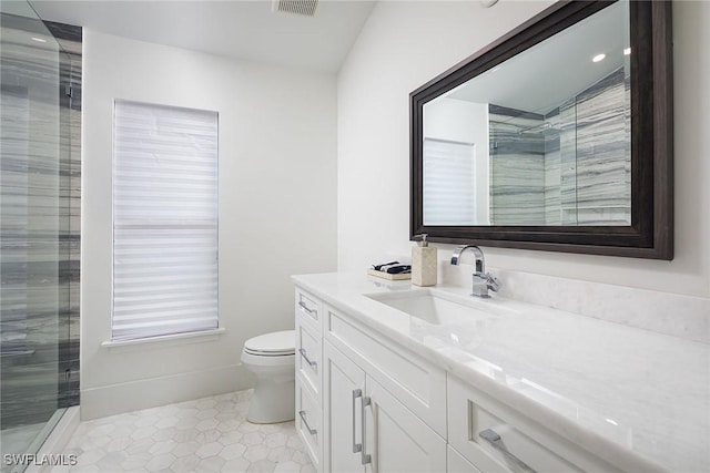 bathroom featuring tile patterned flooring, vanity, toilet, and walk in shower