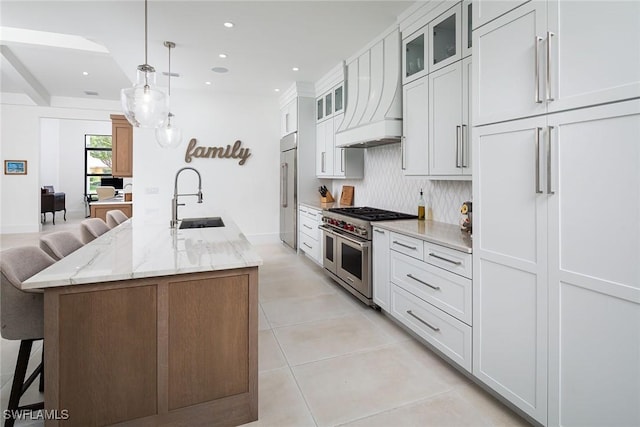 kitchen featuring white cabinets, premium appliances, and a kitchen island with sink